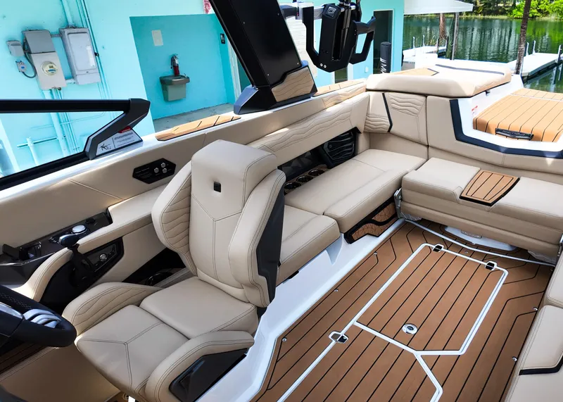 Slide: The Image of 2025 Nautique G23 boat interior with beige seating and wood-style flooring. - 5