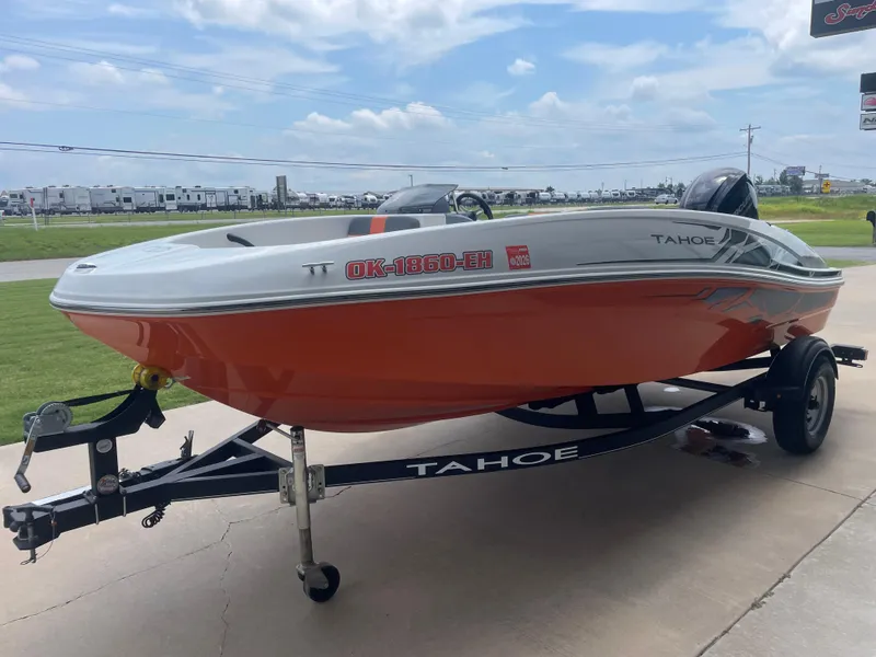 Slide: The Image of 2020 Tahoe T16 boat on trailer, orange hull, parked outdoors under cloudy sky. - 1
