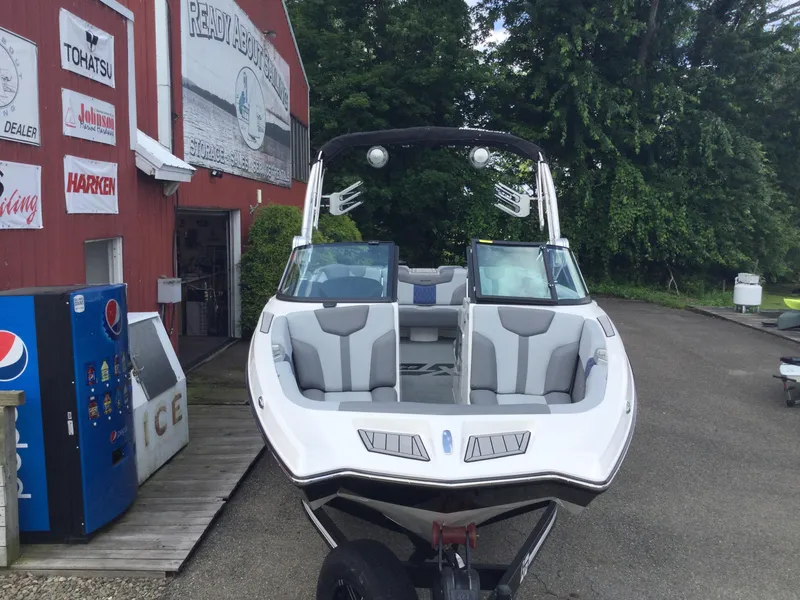Slide: The Image of 2022 MasterCraft XT24 boat parked outside a dealership with signage and vending machines. - 10