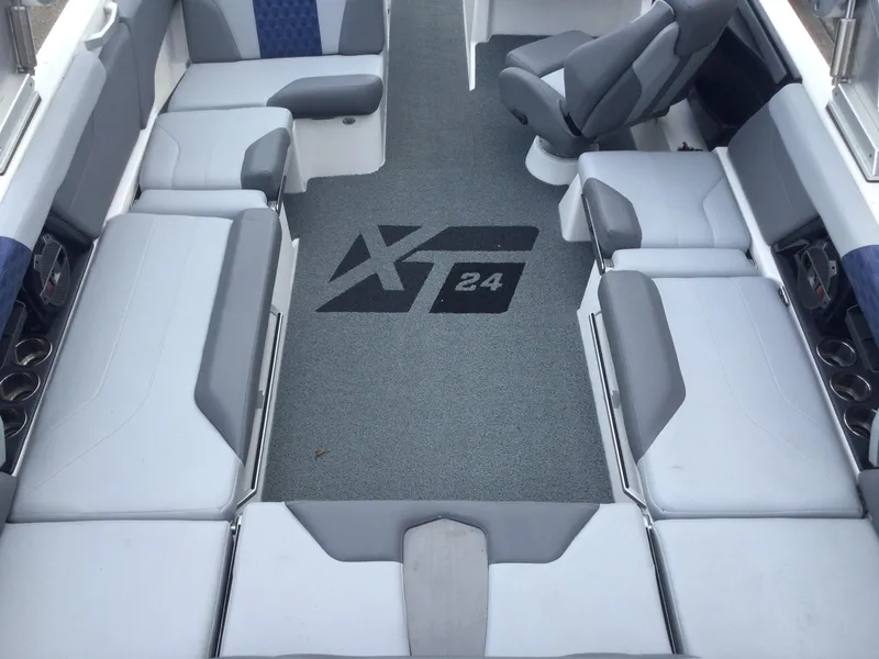 Slide: The Image of 2022 MasterCraft XT24 boat interior with gray seating and logo on carpet. - 15