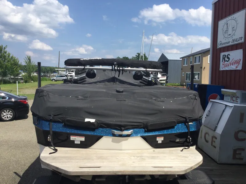 Slide: The Image of 2022 MasterCraft XT24 boat covered, parked near a marina with clear skies. - 5
