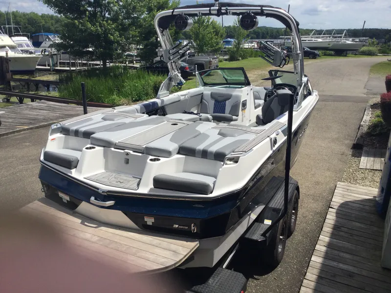 Slide: The Image of 2022 MasterCraft XT24 boat on trailer at marina, featuring sleek design and spacious seating. - 8