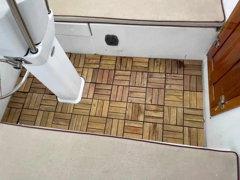 Slide: The Image of Interior of 1987 Nonsuch 30 Ultra sailboat with wooden floor tiles and cushioned seating. - 5