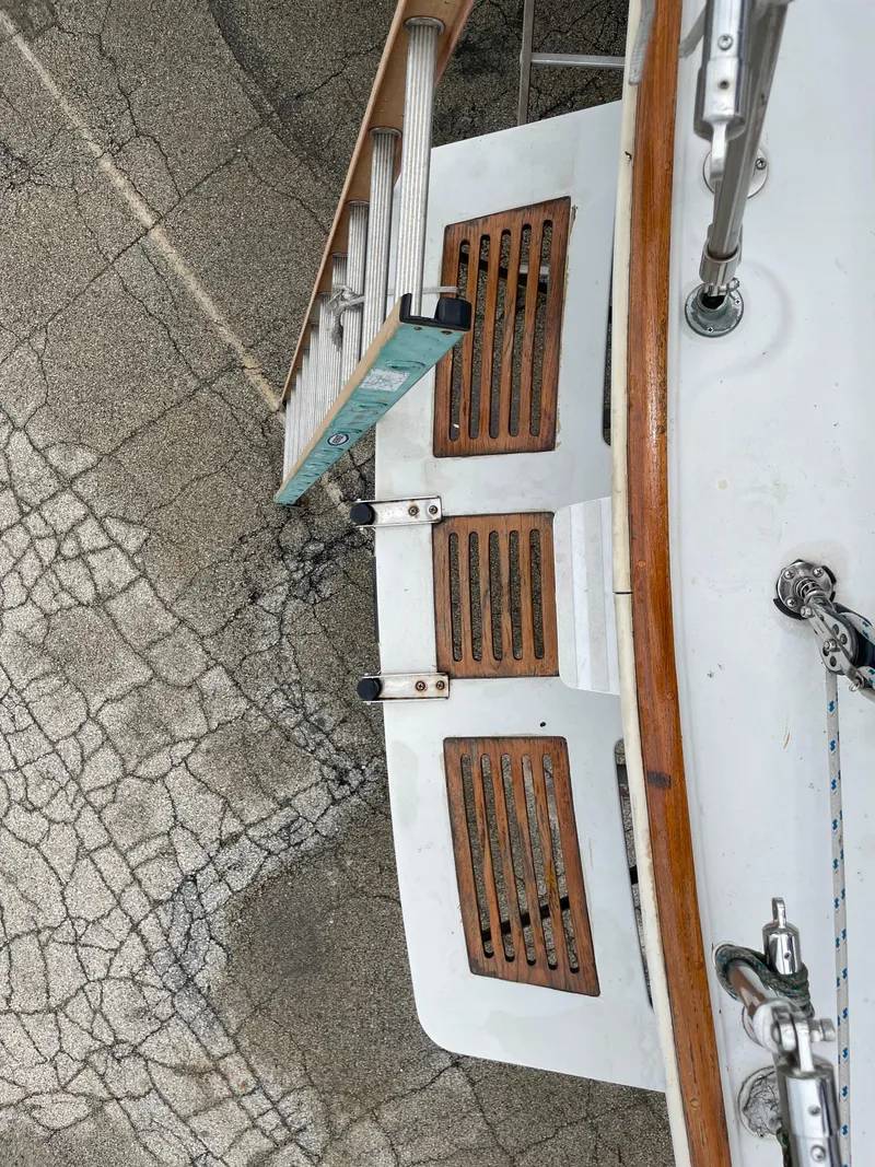 Slide: The Image of 1987 Nonsuch 30 Ultra sailboat stern with wooden slatted steps and ladder on cracked pavement. - 7