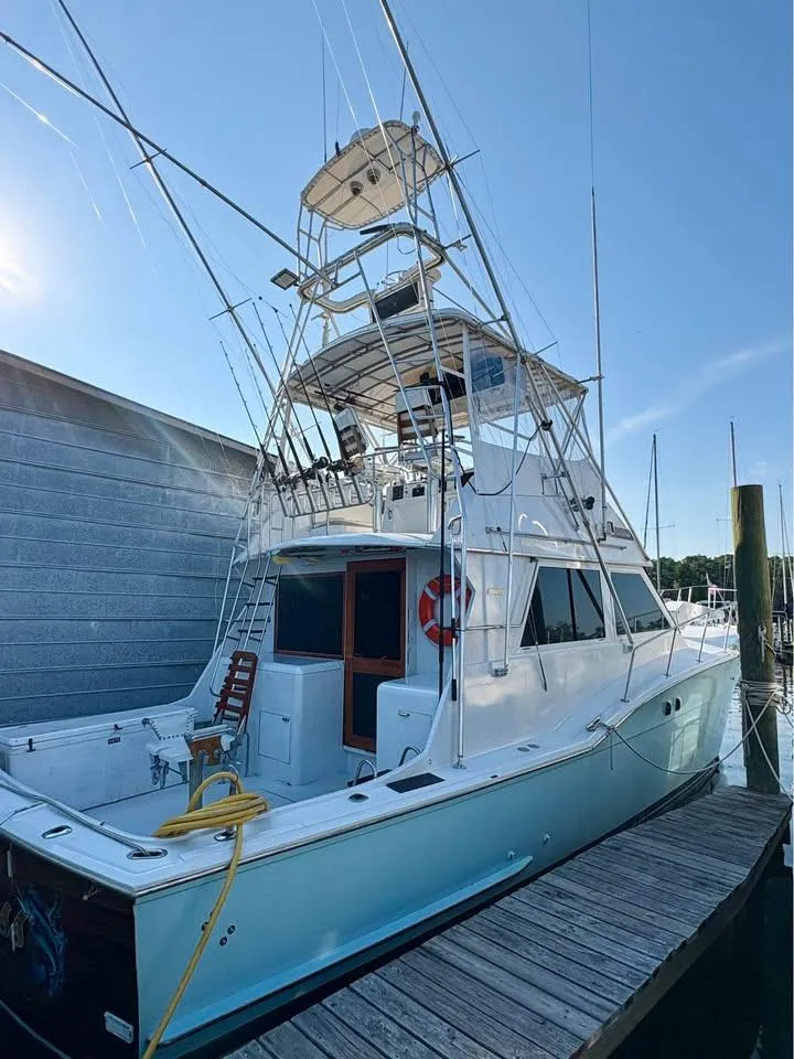 Slide: The Image of 1983 Hatteras 46 Convertible yacht docked at marina under clear blue sky. - 2
