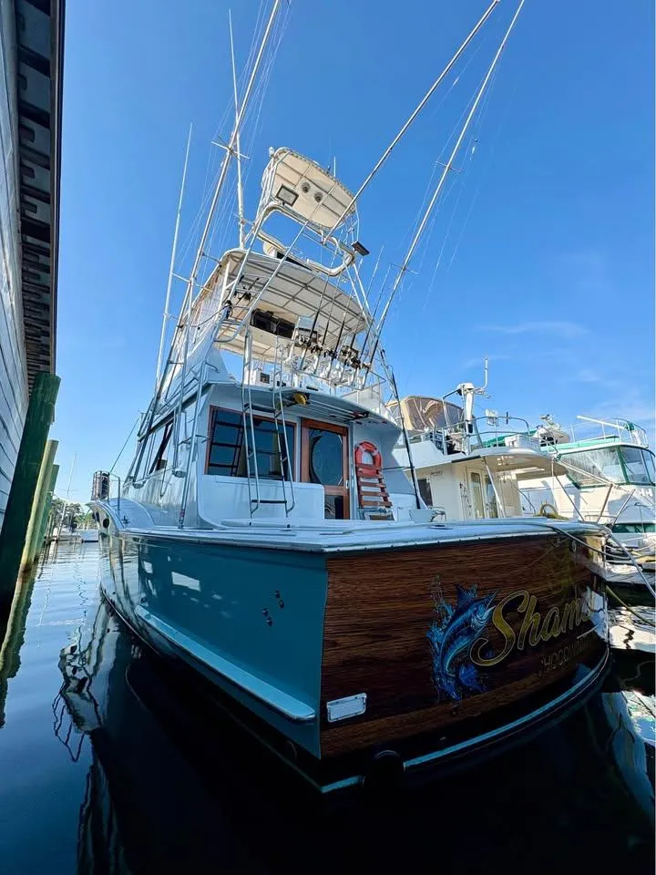 Slide: The Image of 1983 Hatteras 46 Convertible yacht docked, featuring a sleek design and fishing equipment. - 3