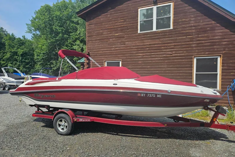 Slide: The Image of Red and white 2008 Bryant 233 boat on trailer, parked near wooden building. - 1