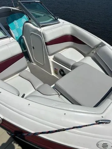 Slide: The Image of 2008 Bryant 233 boat interior with white and maroon seating, docked by the water. - 21