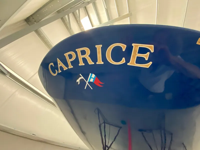 Slide: The Image of 2023 C.W. Hood 32 Daysailer, blue hull with "Caprice" lettering in a boatyard. - 17