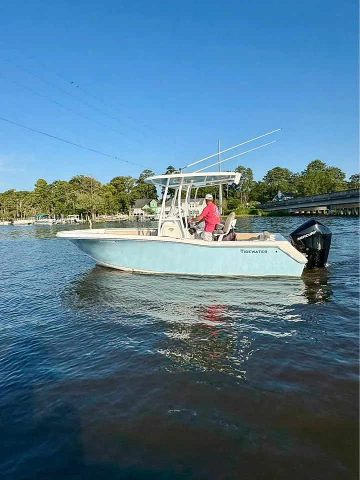 The Image of 2019 Tidewater 220 LXF boat on calm water with a person at the helm. - 0