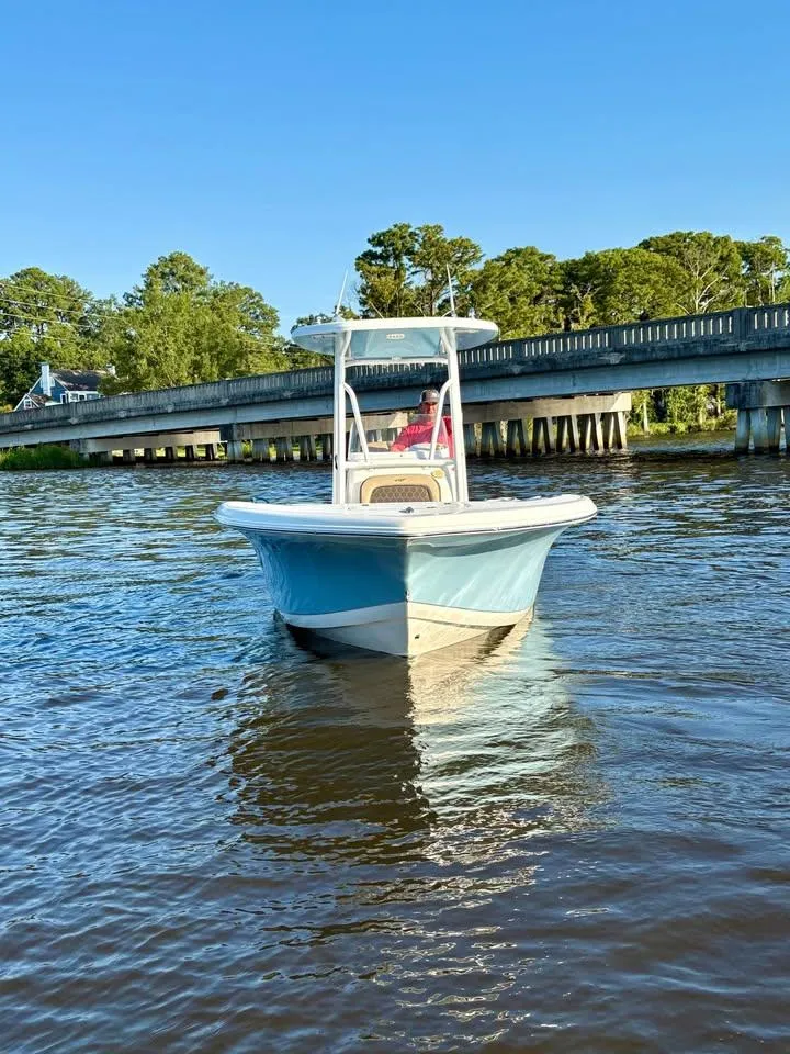 Slide: The Image of 2019 Tidewater 220 LXF boat on a river near a bridge, clear blue sky. - 1