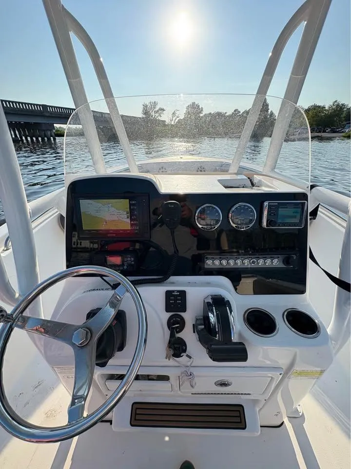 Slide: The Image of 2019 Tidewater 220 LXF boat console with steering wheel and navigation equipment on a sunny day. - 6