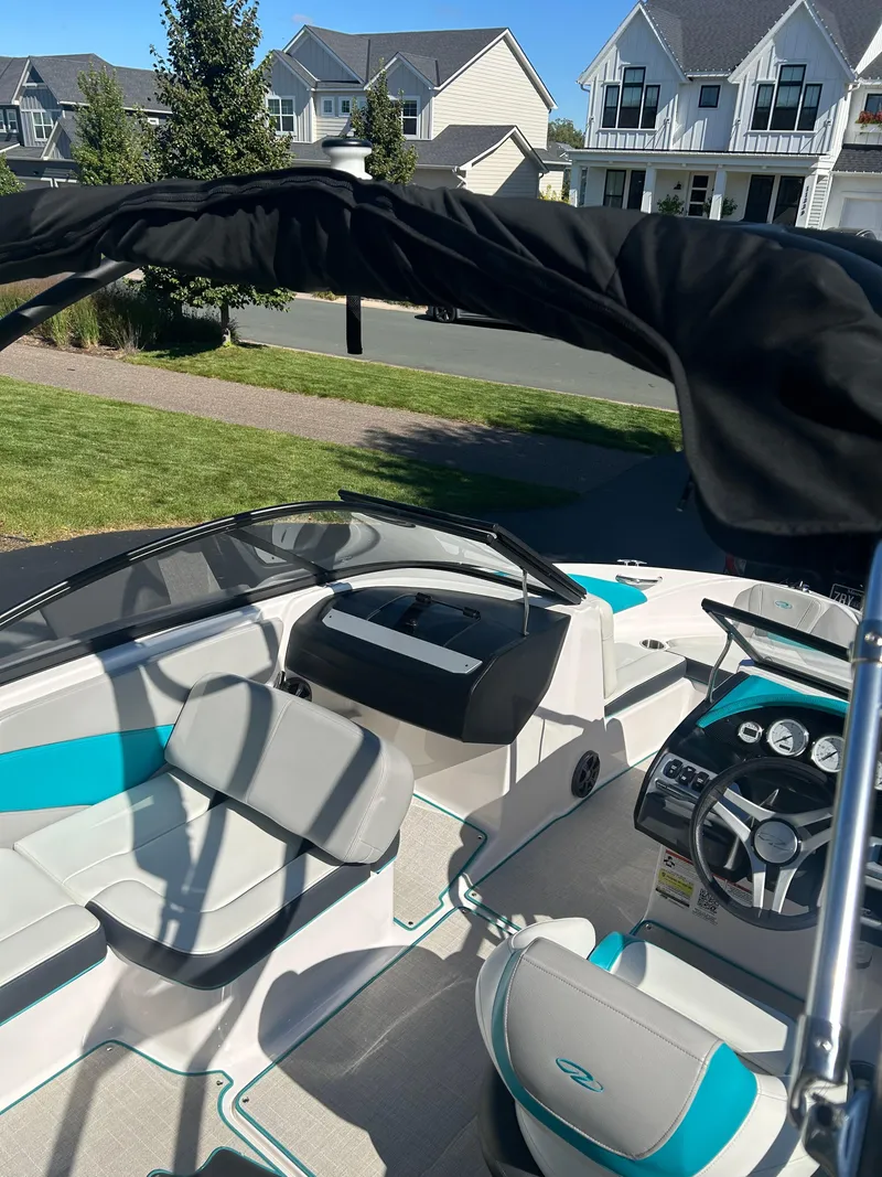 Slide: The Image of 2021 Regal 1900 ES Bowrider boat interior with seating and dashboard, parked in residential area. - 13