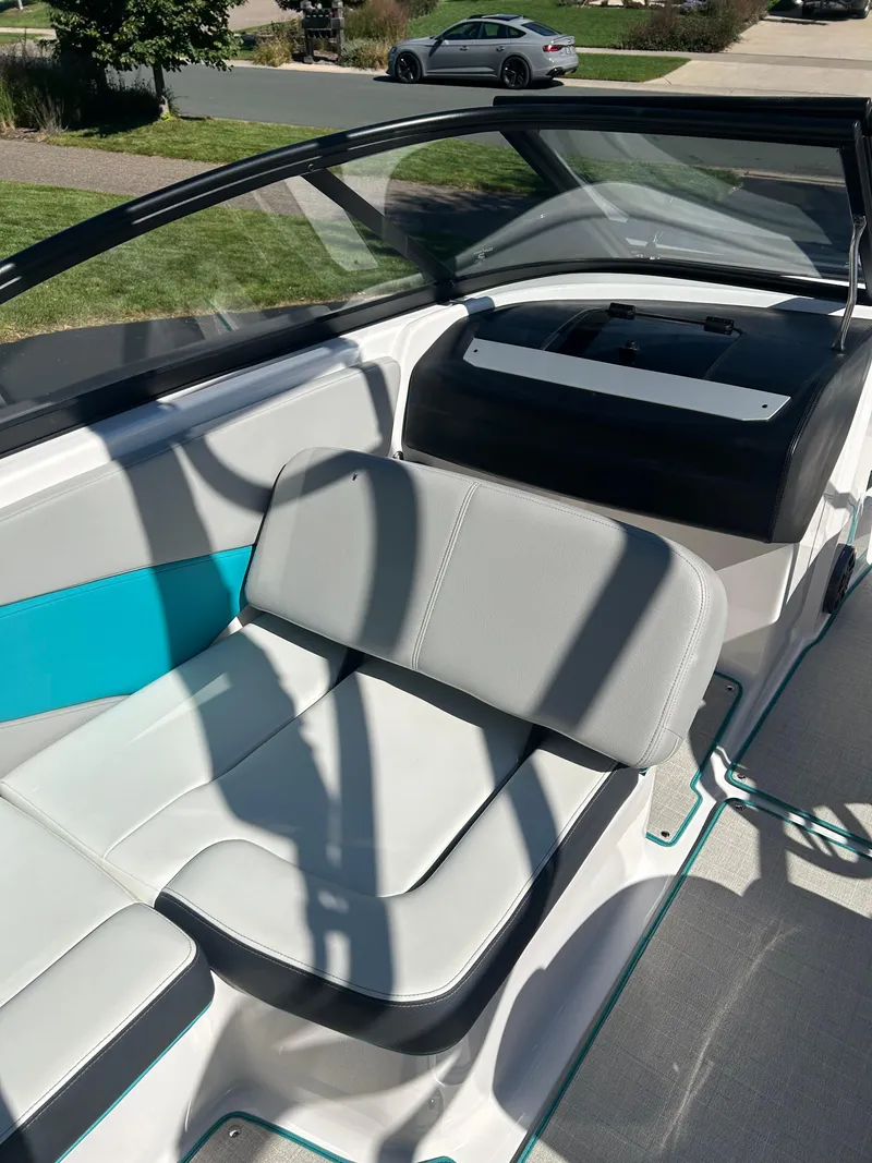 Slide: The Image of 2021 Regal 1900 ES Bowrider interior with gray and teal seating, parked outdoors. - 14