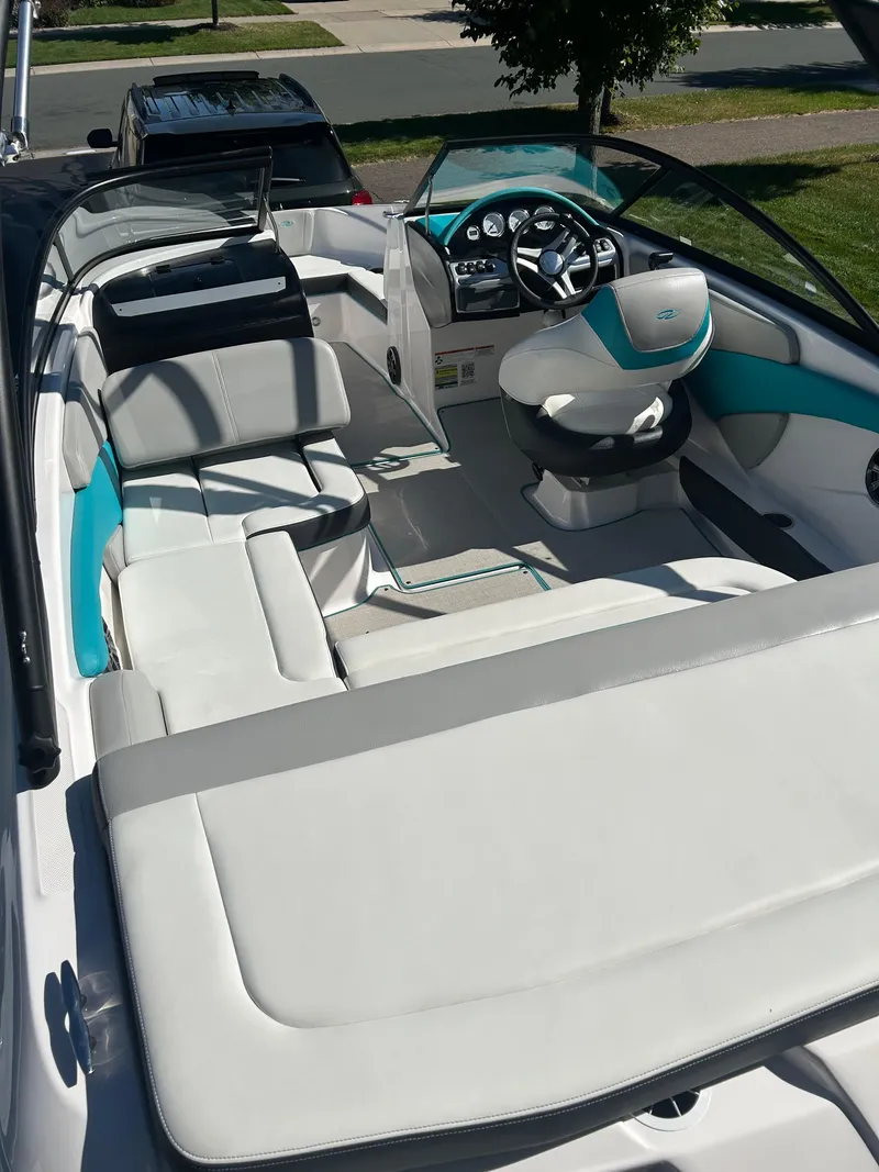 Slide: The Image of 2021 Regal 1900 ES Bowrider interior with white and teal seating, steering console, and open layout. - 16