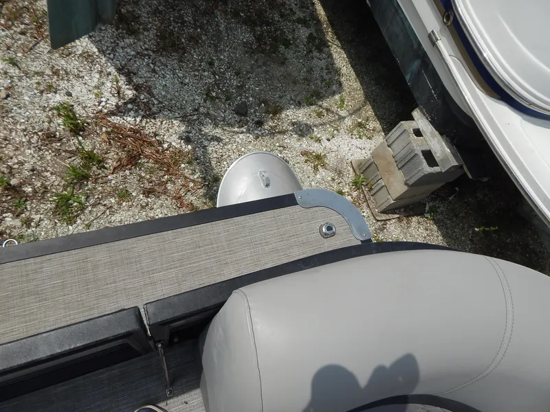 Slide: The Image of 2024 Qwest Splash Pad 822 boat detail with gray upholstery and deck, parked on gravel. - 24