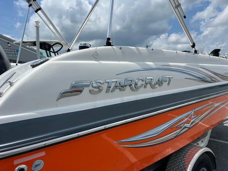 Slide: The Image of 2021 Starcraft Limited 1915 OB boat with orange and white design under cloudy sky. - 8