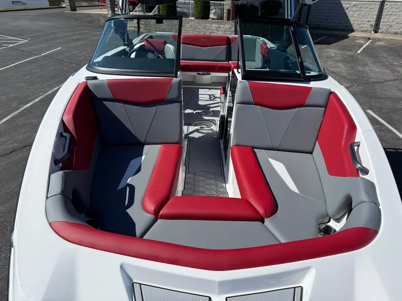 Slide: The Image of 2025 MasterCraft NXT22 boat interior with red and gray seating, parked outdoors. - 12