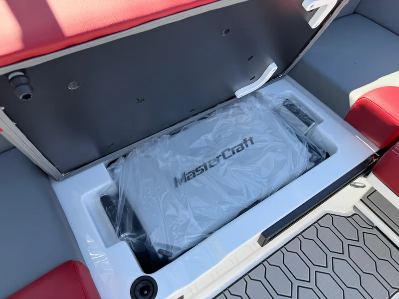 Slide: The Image of 2025 MasterCraft NXT22 boat storage compartment with red and gray seating. - 28