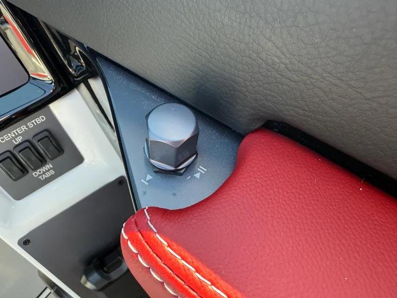 Slide: The Image of 2025 MasterCraft NXT22 boat control panel with red leather trim and adjustment knob. - 40