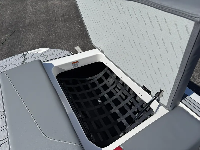 Slide: The Image of 2025 MasterCraft NXT22 boat storage compartment with open lid and netting. - 43