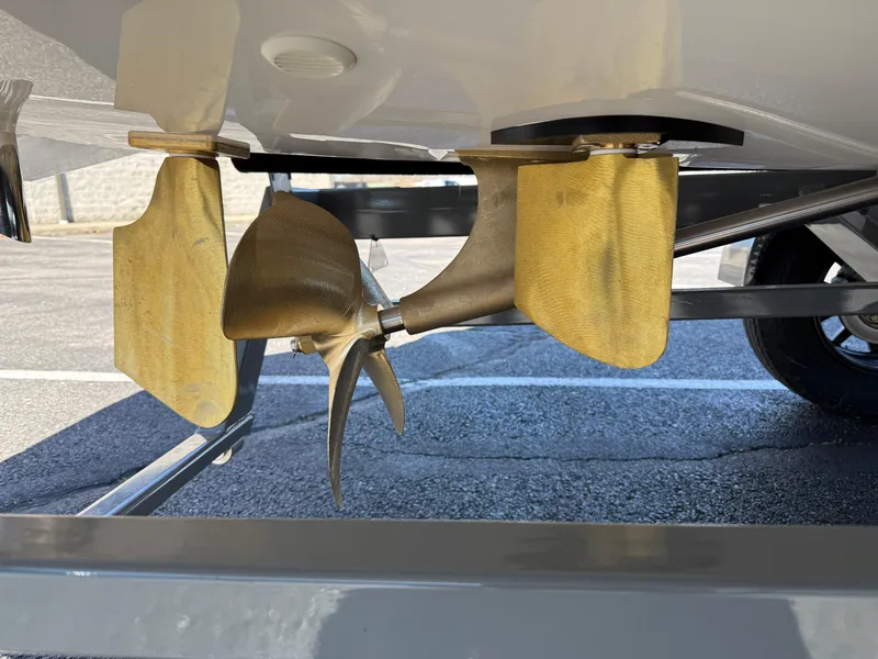 Slide: The Image of 2025 MasterCraft NXT22 boat propeller and rudder detail in a parking lot. - 8