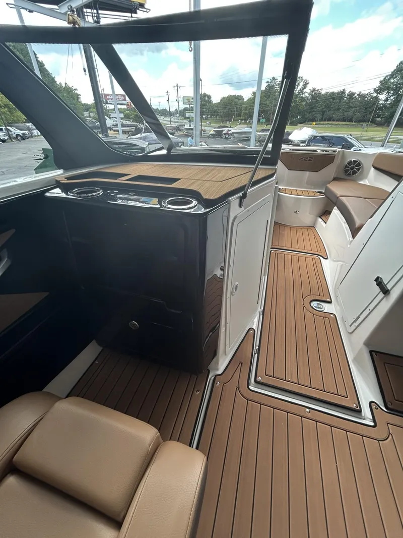 Slide: The Image of 2024 Yamaha Boats 222 S interior with brown seating and wood-style flooring. - 8