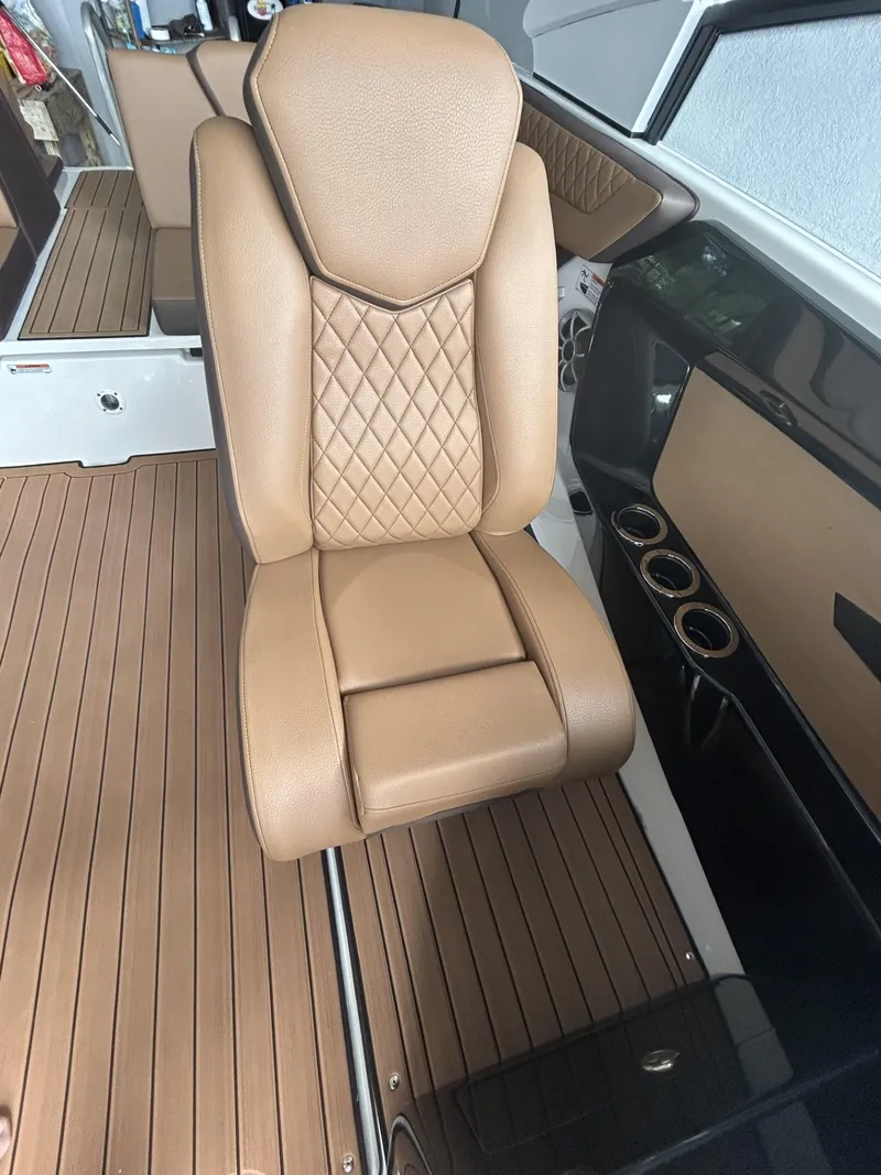 Slide: The Image of 2024 Yamaha Boats 222 S interior with tan leather seat and wood-style flooring. - 9