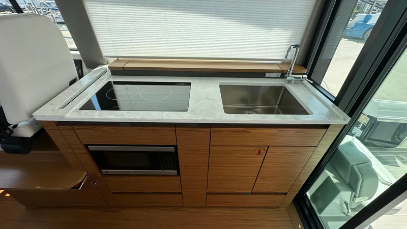 Slide: The Image of Modern kitchen area in 2026 Tiara Yachts 43 LE, featuring sink, stovetop, and microwave. - 27