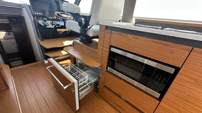 Slide: The Image of Interior of 2026 Tiara Yachts 43 LE featuring helm, microwave, and wooden cabinetry. - 29