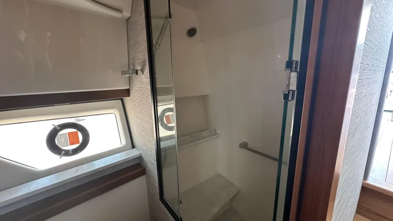 Slide: The Image of Interior of 2026 Tiara Yachts 43 LE, featuring a modern shower with glass door and porthole window. - 46
