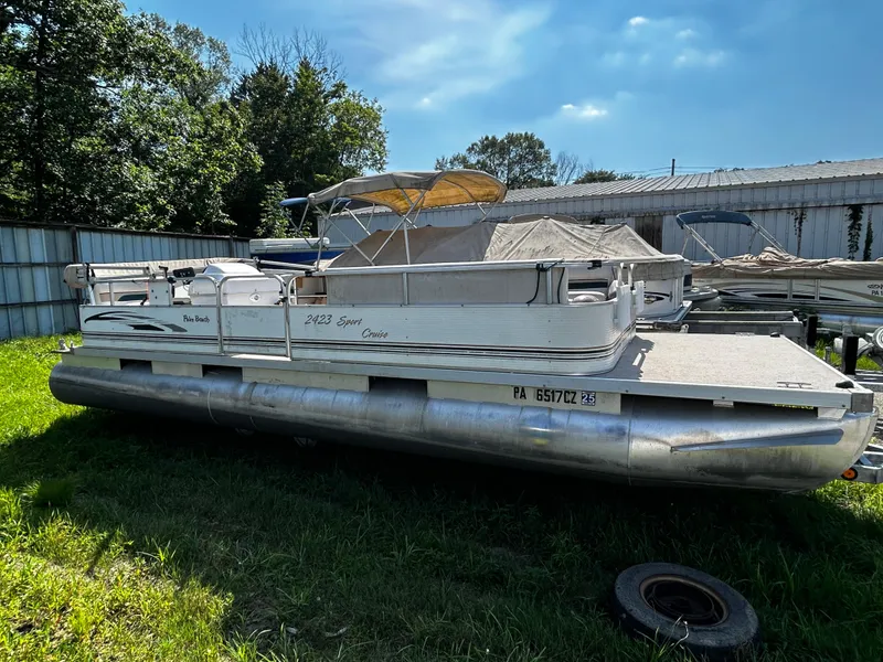 The Image of 2007 Palm Beach Sport Cruise 2423 pontoon boat parked on grass near a metal building. - 0