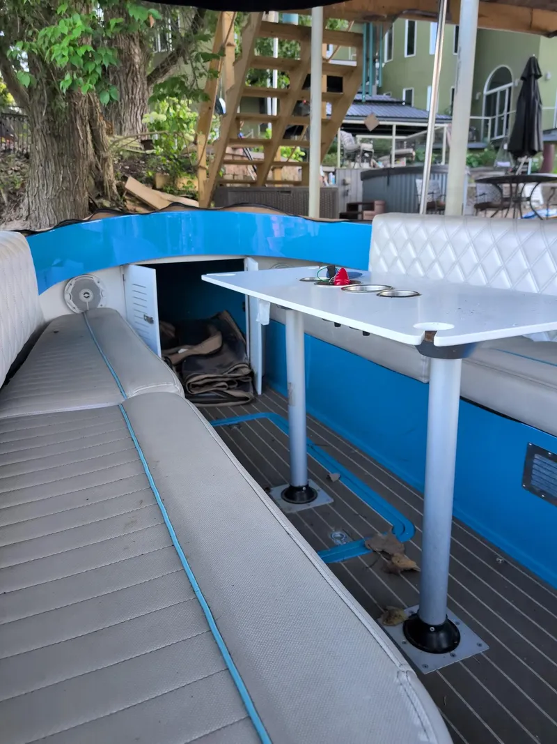 Slide: The Image of 2019 Vision Marine Technologies Fantail 217 interior with seating and table, docked near trees. - 3