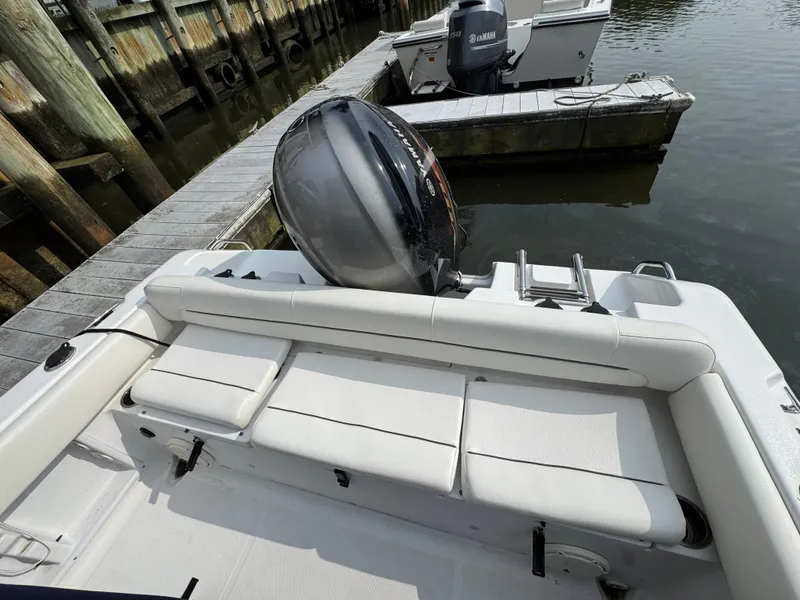 Slide: The Image of 2014 Sea Hunt Ultra 196 boat docked, featuring a blue canopy and white seating. - 18