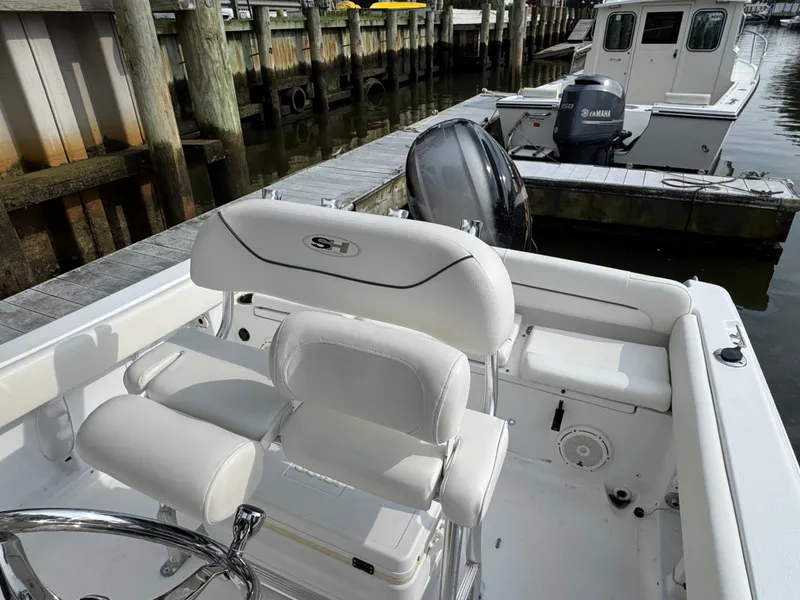 Slide: The Image of 2014 Sea Hunt Ultra 196 boat interior with seating and steering wheel at dock. - 21