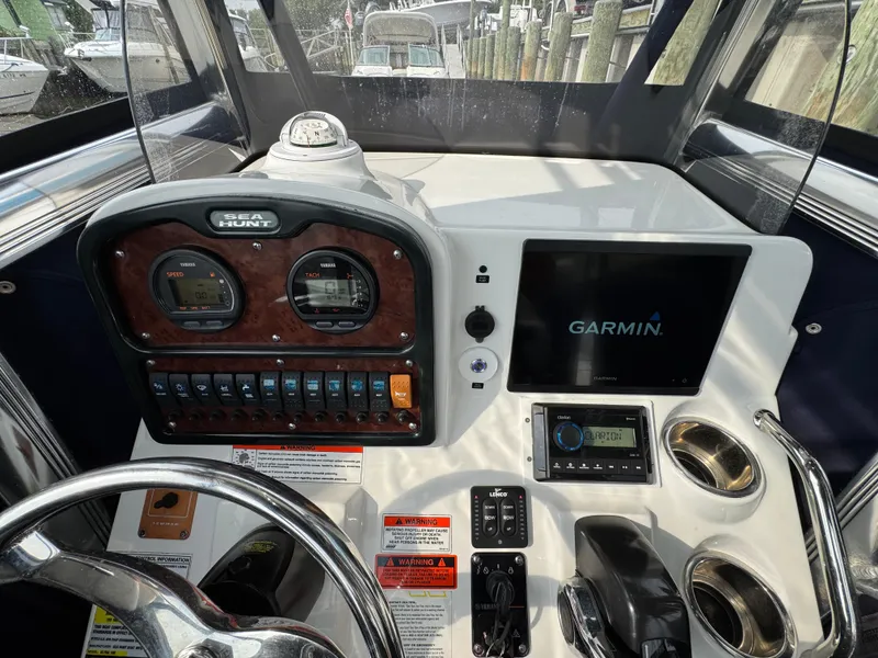 Slide: The Image of 2014 Sea Hunt Ultra 196 boat with blue canopy, docked at marina. - 5