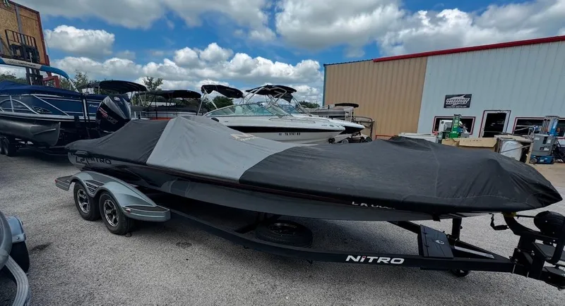 Slide: The Image of 2021 Tracker Nitro Z21 SC boat covered, parked outdoors near other boats. - 12