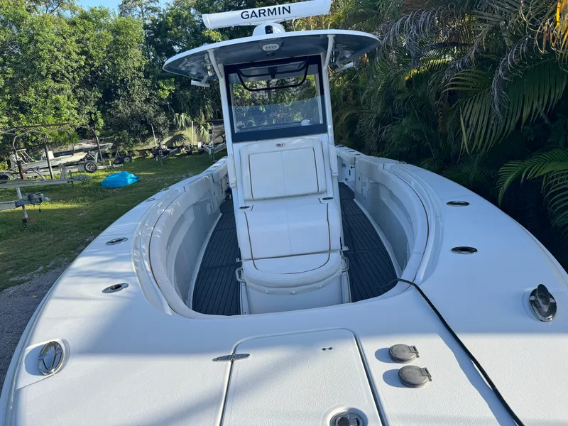 Slide: The Image of 2021 Sea Hunt Gamefish 30 Coffin Box boat with Garmin equipment, surrounded by lush greenery. - 2