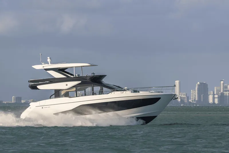 Slide: The Image of 2025 Cruisers Yachts 57 Fly cruising on water with city skyline in background. - 2