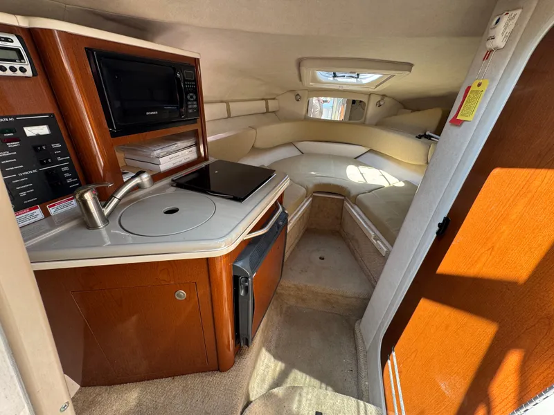 Slide: The Image of 2008 Sea Ray 240 Sundancer cabin interior with kitchenette, sink, and cozy seating area. - 13