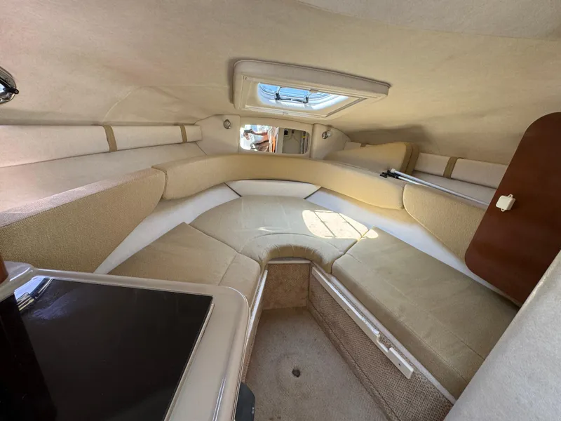 Slide: The Image of 2008 Sea Ray 240 Sundancer cabin interior with beige seating and overhead hatch. - 14