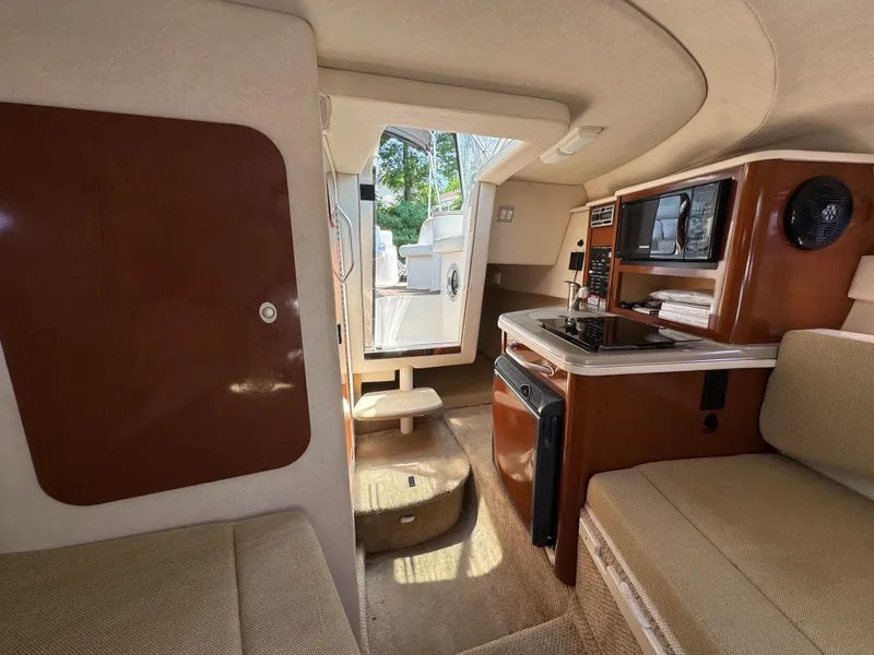 Slide: The Image of Interior of 2008 Sea Ray 240 Sundancer boat with kitchenette and seating area. - 15
