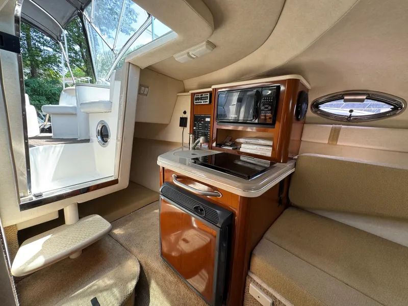 Slide: The Image of Interior of 2008 Sea Ray 240 Sundancer boat with kitchenette and seating area. - 16