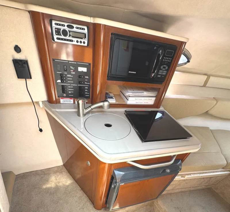 Slide: The Image of 2008 Sea Ray 240 Sundancer cabin kitchen with microwave, sink, and control panel. - 18