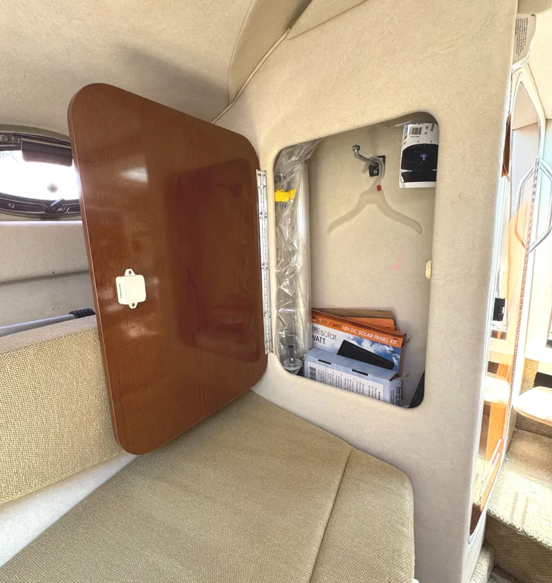 Slide: The Image of 2008 Sea Ray 240 Sundancer cabin storage with open wooden cabinet and solar panel kit. - 19