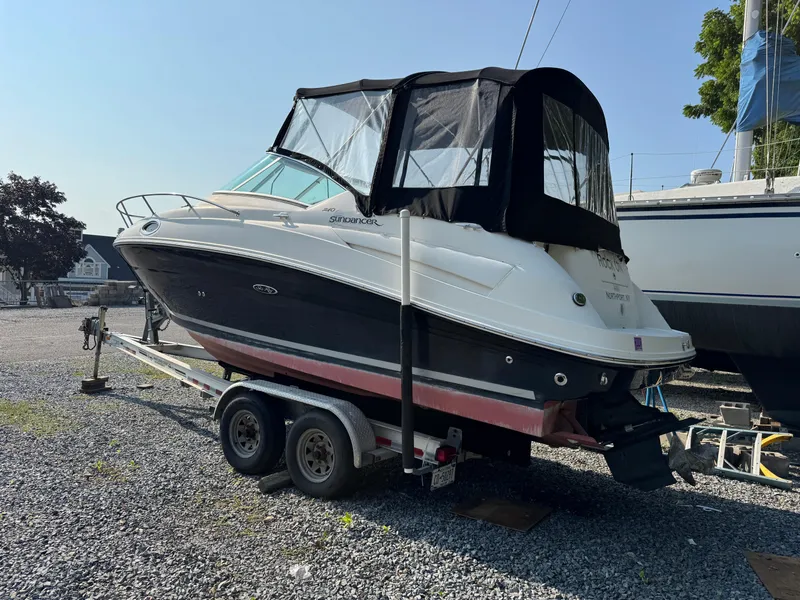 Slide: The Image of 2008 Sea Ray 240 Sundancer boat on trailer, parked on gravel lot. - 2