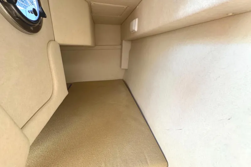 Slide: The Image of Interior cabin of 2008 Sea Ray 240 Sundancer, featuring beige upholstery and a porthole window. - 22