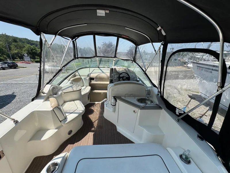 Slide: The Image of 2008 Sea Ray 240 Sundancer interior with seating, steering wheel, and sink under canopy. - 6