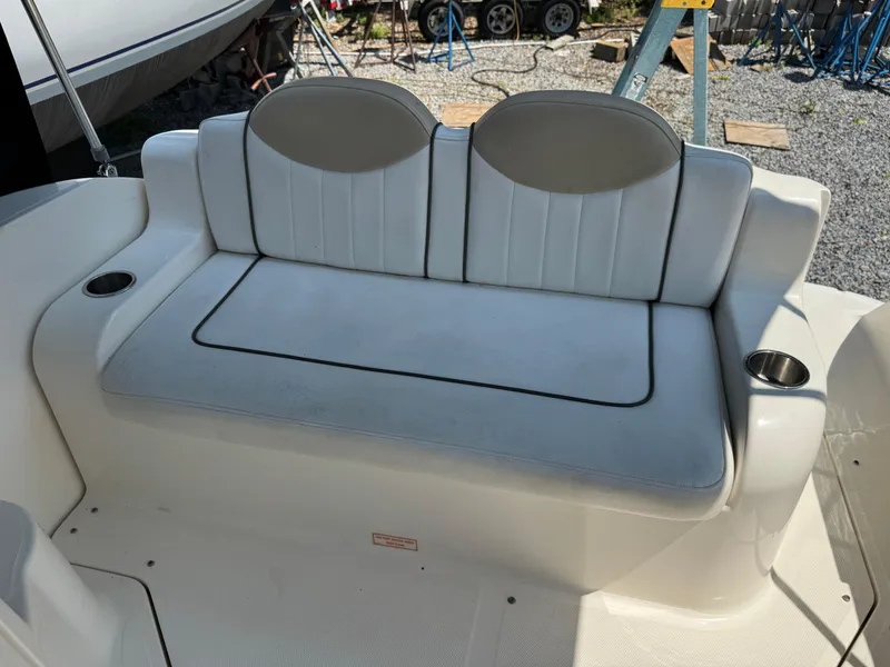 Slide: The Image of 2008 Sea Ray 240 Sundancer boat seating with cup holders, docked on gravel. - 9