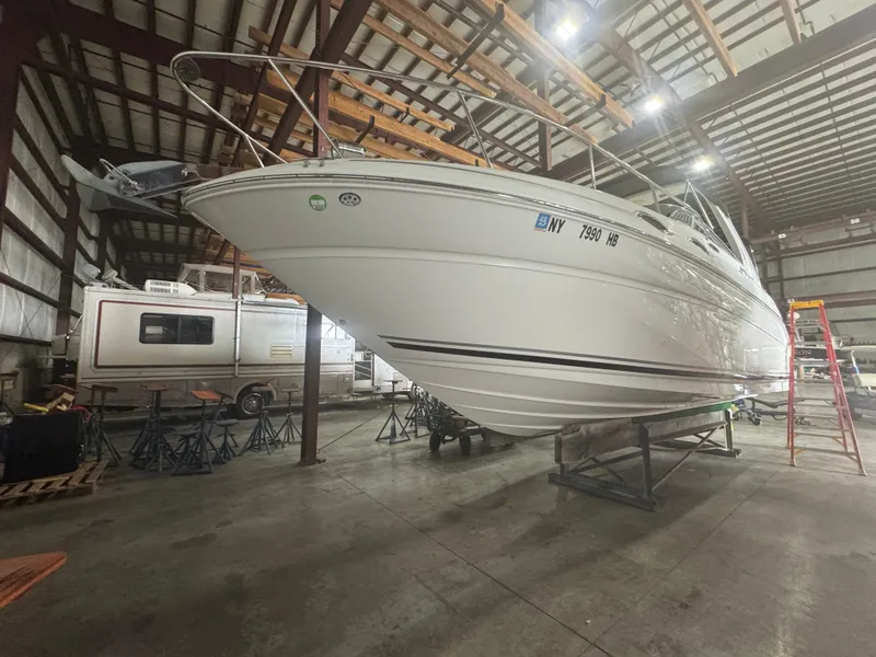 The Image of 2004 Sea Ray 260 Sundancer boat in storage, elevated on stands in a warehouse. - 0